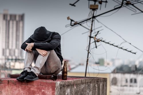 Understanding How Substance Abuse Increases Risk of Suicidal Thoughts - young man in hoodie on roof with alcohol
