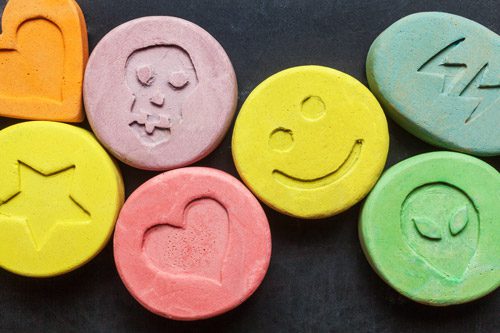 closeup of colorful tablets with imprints of hearts, stars, and smiley faces - ecstasy - mdma